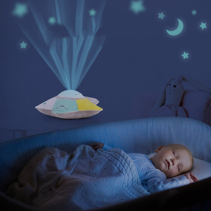 Star-shaped LED projector night light plush in blue, yellow, orange on a bed