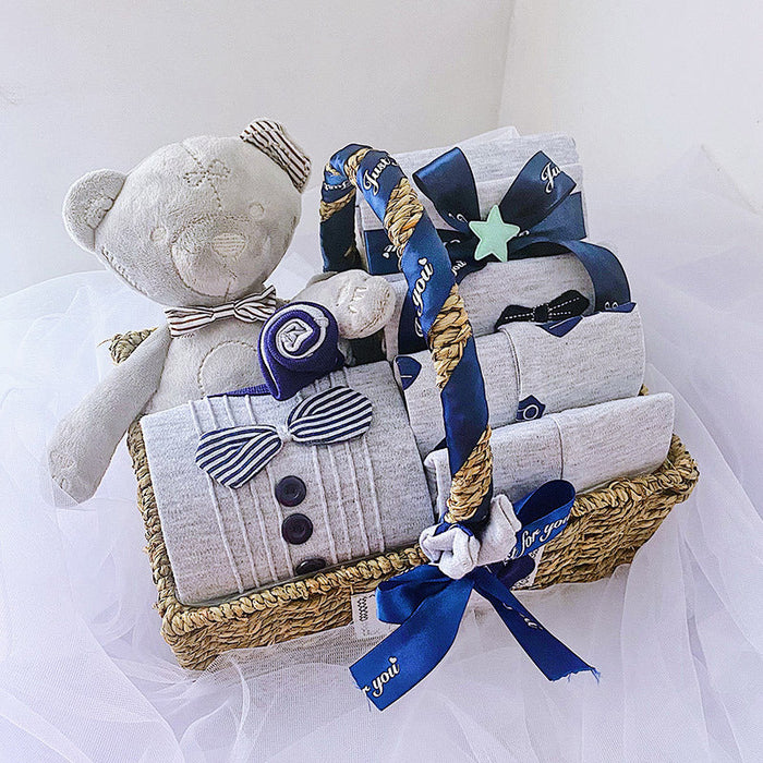 Baby clothes gift set with gray bear plush, striped outfit, and ribbon in woven basket