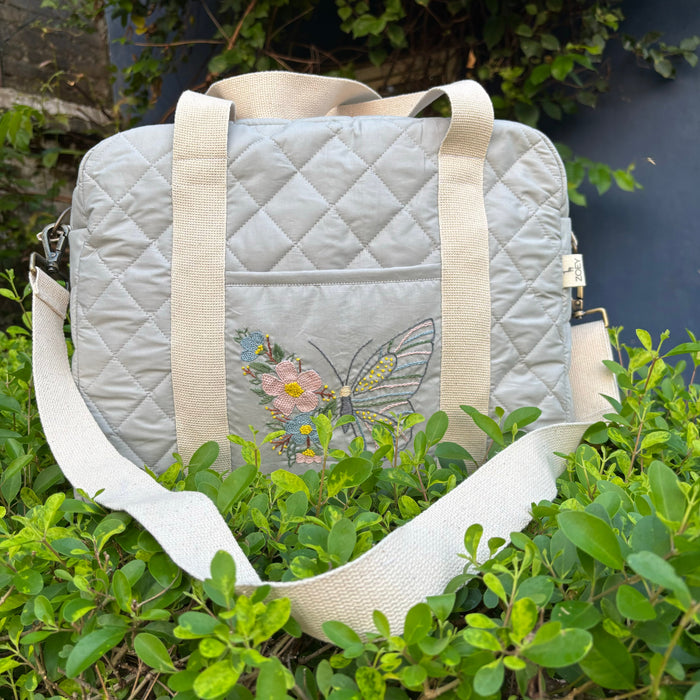 Quilted white nappy bag with embroidered butterfly and beige shoulder straps