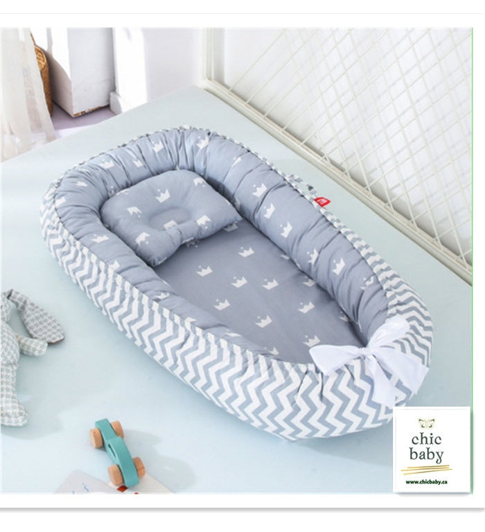 Portable baby crib nest with gray chevron outer edges and light gray printed inner pad
