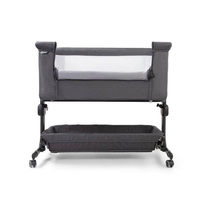Grey bedside crib with padded rails and wheels, two-level design