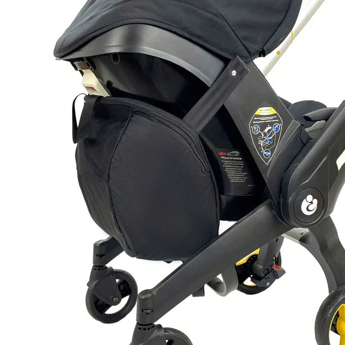 Black stroller storage bag attached to stroller frame, with zip pocket and straps