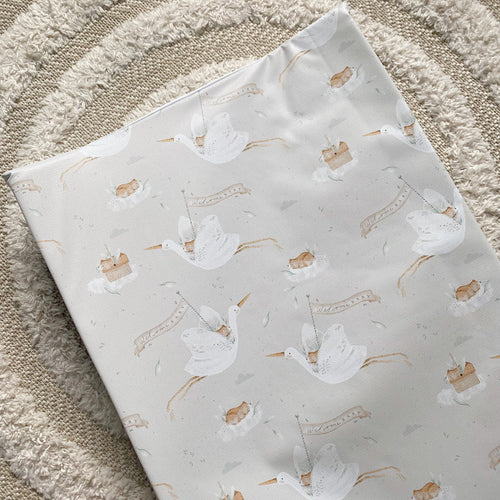 White wedge baby changing mat with stork, boot, and welcome baby pattern
