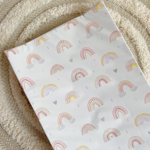 Wedge changing mat with pastel rainbow print on white fabric, laid flat