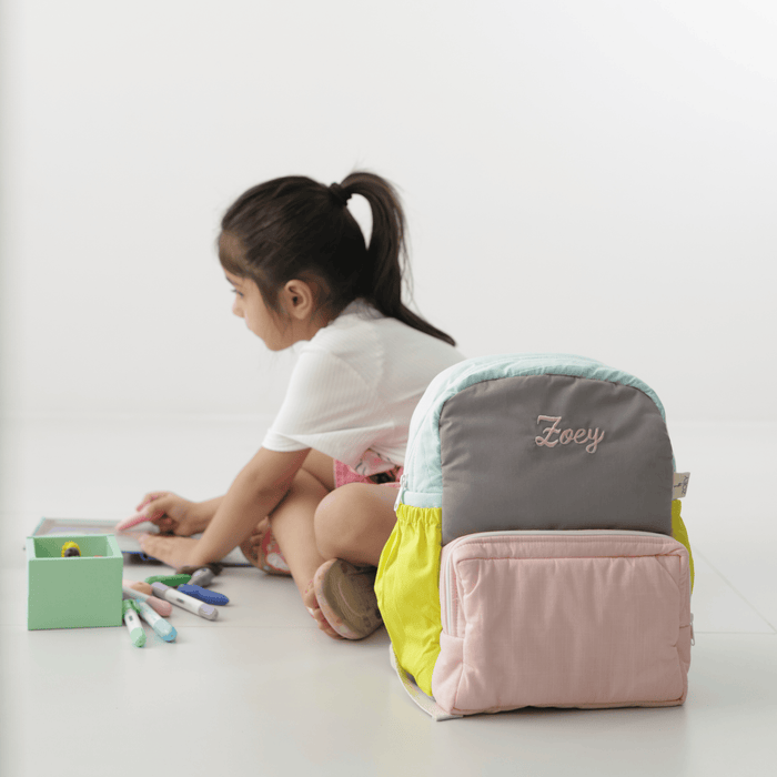Kids backpack with gray, mint, and lime yellow panels; pink front pocket; “Zoey” logo.