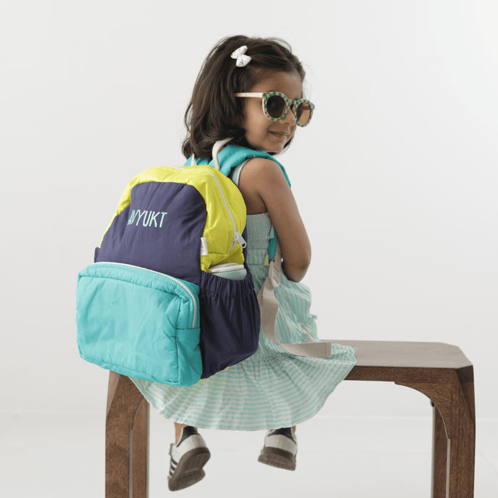 Kids backpack with navy, lime, and teal panels, front pocket and top handle