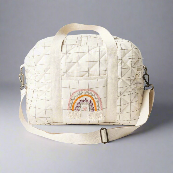 Cream grid nappy bag with top handle and rainbow embroidered front panel