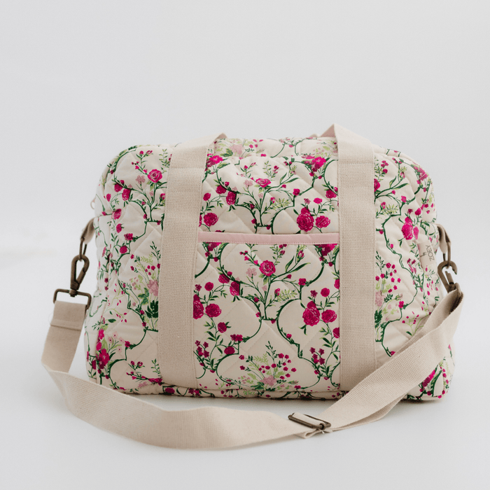 Quilted floral cotton nappy bag with top zip, short handles, and long shoulder strap